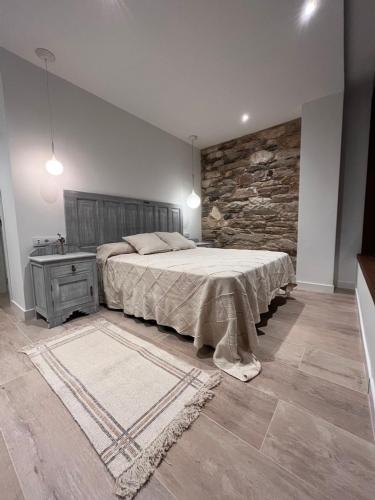 a bedroom with a large bed and a stone wall at Caraxolas in Lugo