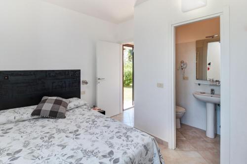 una camera da letto con un letto e un bagno con un lavandino di Artemisia negli ulivi b&b a Magliano in Toscana