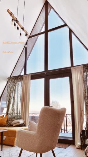 a living room with a chair and a large window at Klek 77 Luxury Chalets near Jahorina in Paočići
