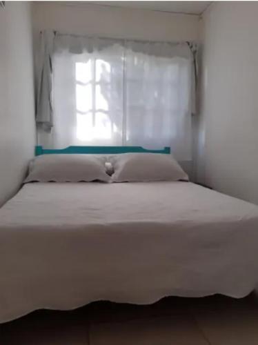 1 cama blanca con ventana en un dormitorio en Cabaña para exploradores 600 mts del centro en El Calafate