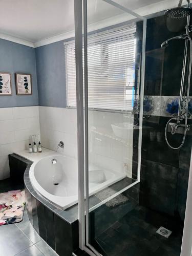 a bathroom with a shower and a tub and a sink at Lielies Guesthouse in Parys