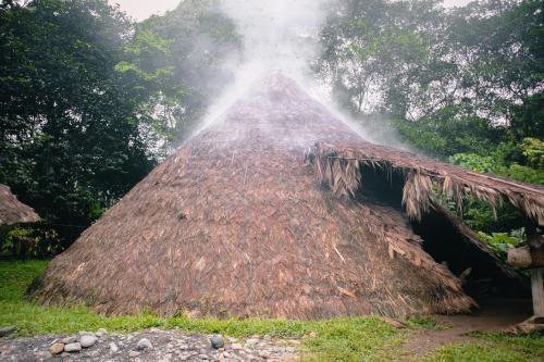 Une cabane au toit de chaume avec fumée en sortant dans l'établissement Bribri Eco Aventura, à Talamanca