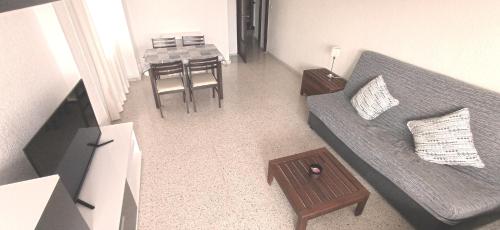 uma pequena sala de estar com um sofá e uma mesa em Apartamento Rincon de Loix, soleado, zona jardines y piscina, y zona exterior para aparcar y a la playa a 300,00 mts. em Benidorm