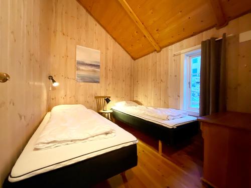 two beds in a room with wooden walls and a window at The blacksmith's place - Cozy Rorbu in Lofoten in Sørvågen