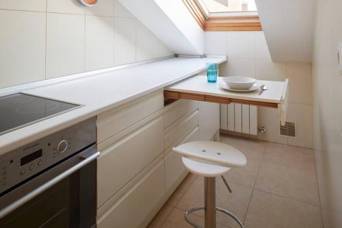 uma pequena cozinha com uma mesa e um lavatório em Apartamento con terraza a un paso de la playa em Gijón