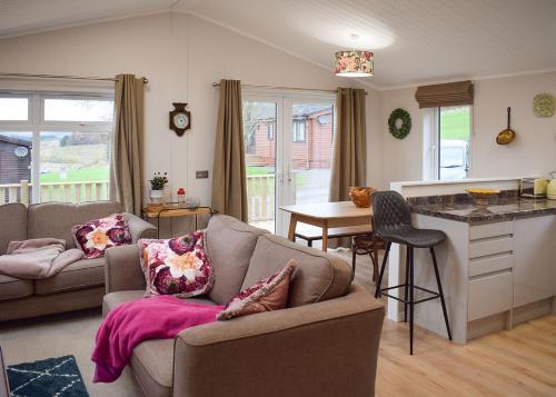 a living room with a couch and a table and a kitchen at Clear Sky Lodge Park in Falstone