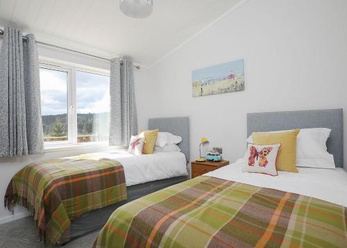 een slaapkamer met 2 bedden en een raam bij Clear Sky Lodge Park in Falstone