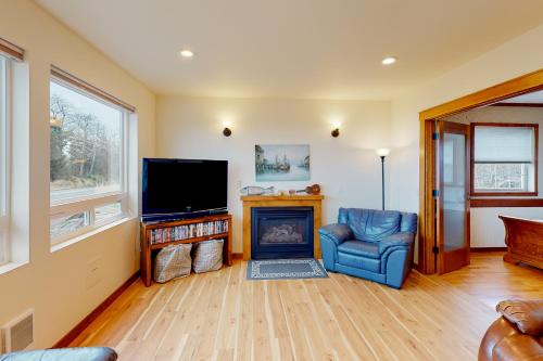 a living room with a fireplace and a television at Cape Satisfaction in Ilwaco