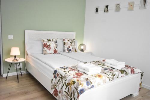 um quarto com uma cama branca e um cobertor floral em Homey Luxury- entire house, free parking, yard em Cluj-Napoca