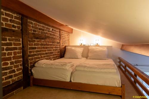 a bed in a room with a brick wall at Hoeve Espewey - Studio 