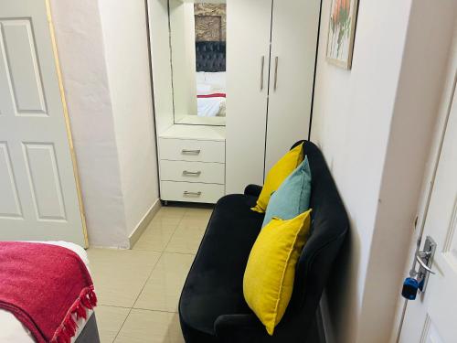 a black couch with yellow pillows sitting in a room at 36 frere road shelly beach , margate in Margate