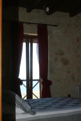 a bedroom with a window with red curtains at Kapsali House in Keratokampos
