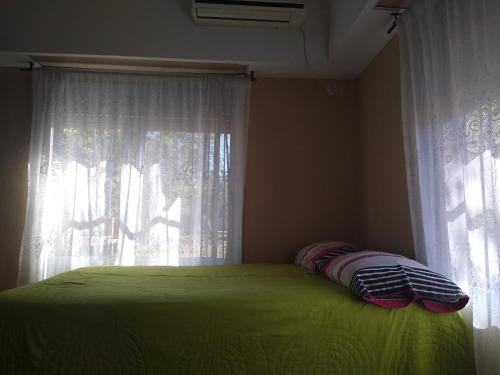 1 dormitorio con cama verde y ventana en Cuatro Estaciones en General Rodríguez