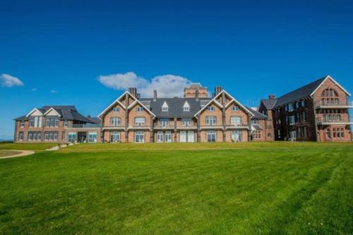 a large brick building with a large grass field at Stunning Sea View Two Bed Two Bathroom Apartment in Porthcawl