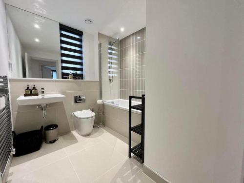a bathroom with a toilet and a sink and a bath tub at Stunning Sea View Two Bed Two Bathroom Apartment in Porthcawl