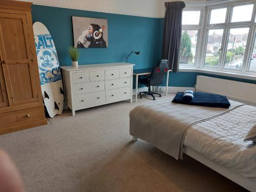 um quarto com uma cama e uma prancha de surf em Beach House, with BBQ lodge and Hot Tub! em Bournemouth