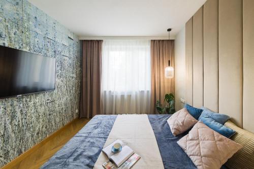 a bedroom with a bed with a tv on a wall at Modern Apart 23 in Olsztyn