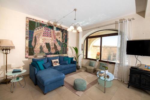 a living room with a blue couch and a tv at Ta’ Giljan B&B Gozo in Xagħra