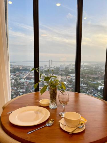 a wooden table with plates and glasses and a window at Verdela Pollux Meisterstadt Batam apartement in Batam Center