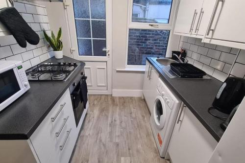 a kitchen with a stove and a sink and a microwave at Entire House Near City Centre with Parking Permit (3 bedrooms, Sleeps 8) in Liverpool