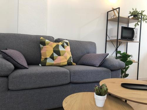 sala de estar con sofá gris con almohadas y mesas en La Alkarra, en Alcalá del Júcar
