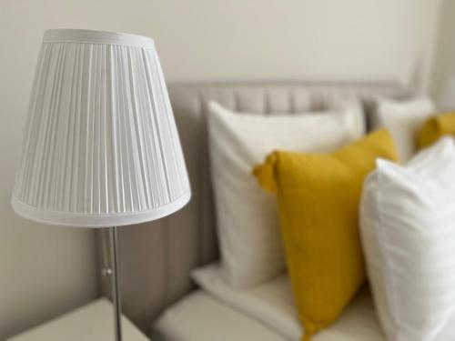 a white lamp sitting next to a bed with pillows at Nature in the City lower storey Bestern in Szeged