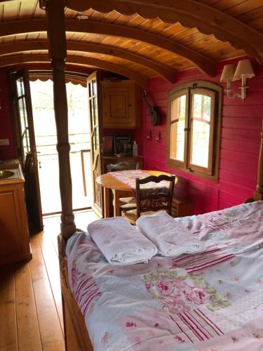 a bedroom with a bed with pink walls and a table at ROULOTTE CAPUCINE in Ablon