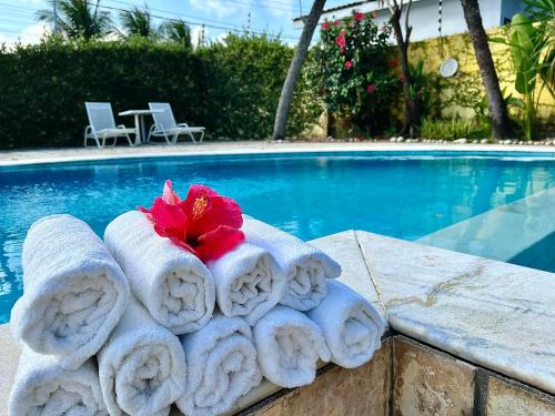a pile of towels sitting next to a swimming pool at Casa Bonita da Barra - 04 quartos, 170m da praia barramar in Barra de São Miguel