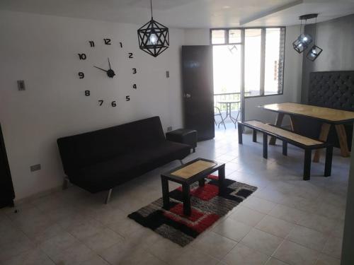 a living room with a couch and a clock on the wall at Hermoso apto a una cuadra de la playa rodadero in Gaira