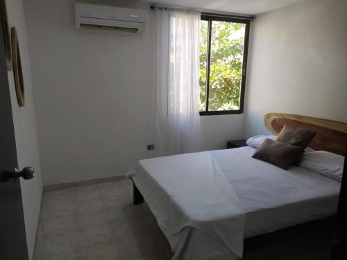 a bedroom with a large bed and a window at Hermoso apto a una cuadra de la playa rodadero in Gaira