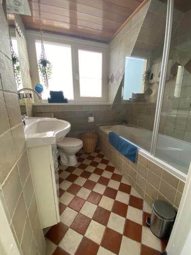 y baño con bañera, aseo y lavamanos. en B&B Zonnedael en Oosterend