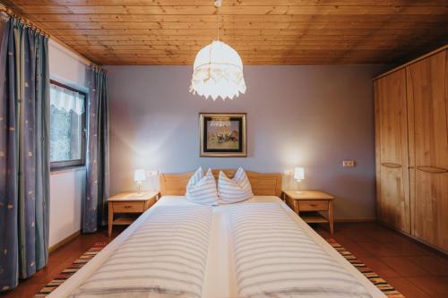 a large bed in a bedroom with a chandelier at Residence Obermoarhof - Family Apartments with Pool & Playground in Vandoies