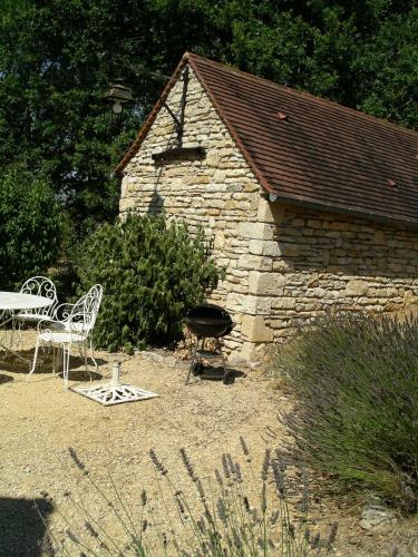 a stone building with a grill and a table and chairs at Pech Cujoul in Gourdon-en-quercy