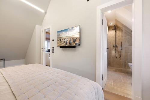 ein Schlafzimmer mit einem Bett und einem Fernseher an der Wand in der Unterkunft Haus Süderjen in Westerland