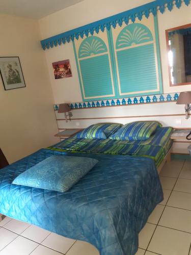 a bedroom with a bed with blue sheets and a window at Résidence Hôtelière Le Carayou in Les Trois-Îlets