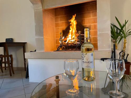 - une bouteille de vin et deux verres sur une table devant une cheminée dans l'établissement Gîte des Longs Champs, à Blosville
