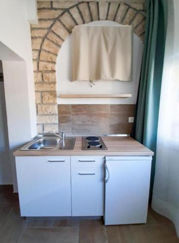 a small kitchen with a sink and a brick wall at Apartment Nina in Rovinj