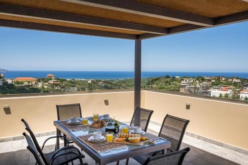 a table on the balcony with a view of the ocean at Casa Belvedere Apartments in Kournás