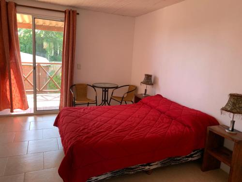 a bedroom with a red bed and a table and chairs at Posada Cova Del Sol in La Pedrera