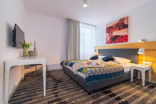 a bedroom with a bed and a desk and a television at Apartament DREAM in Pogorzelica