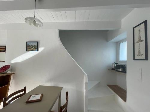 a dining room with a table and a staircase at La Petite Maison, charmant Penty coeur de village in Séné