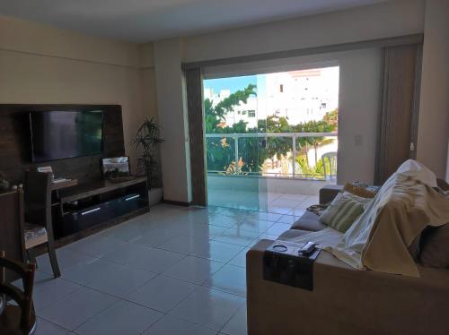 a living room with a couch and a large window at Seu Apê na Enseada Azul - Bacutia !!! in Guarapari