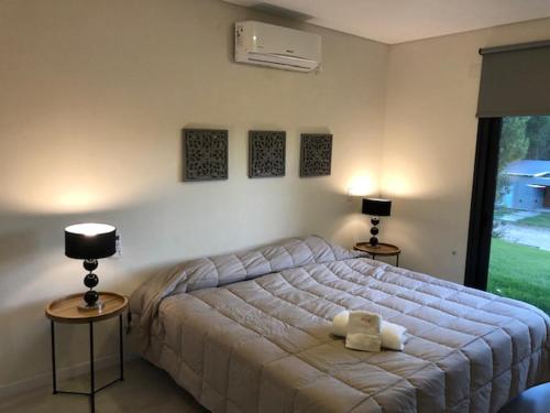 1 dormitorio con 1 cama grande, 2 mesas y 2 lámparas en casas barrio cerrado costa esmeralda en Pinamar