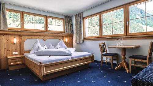 a bedroom with a bed and a table and windows at Hotel Alpina in Ischgl