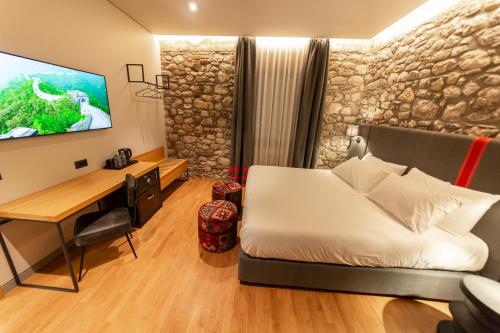 a bedroom with a bed and a desk and a tv at Melesin Distillery in Leskovik