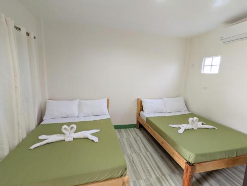 2 camas en una habitación con verde y blanco en Charlina Inn Panglao, en Panglao