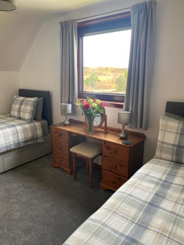 a bedroom with a desk and a window with flowers on it at Almondbank Self Catering Apartment in Skeabost