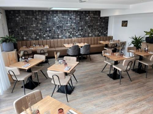 een restaurant met houten tafels en stoelen en een bank bij Hotel Duinlust in Domburg