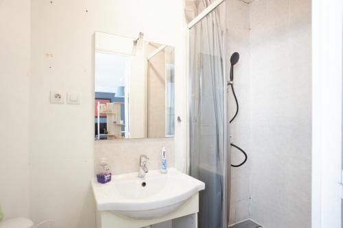 La salle de bains blanche est pourvue d'un lavabo et d'une douche. dans l'établissement Appartement Sympa entre Paris et Disneyland, à Noisy-le-Grand
