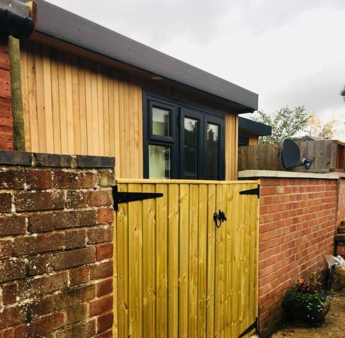 a house with a wooden gate and a brick wall at Cabin Retreat in the heart of Warwick. in Warwick